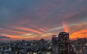 Eine Stadtansicht im Abendrot mit beleuchteten Gebäuden und einem Sonnenuntergangshimmel.