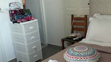 A bedroom with a bed, a wooden chair, a white storage unit, and a patterned pillow.