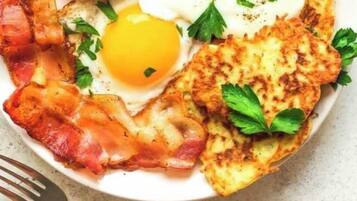 Un plato con tocino, huevos y patatas ralladas.