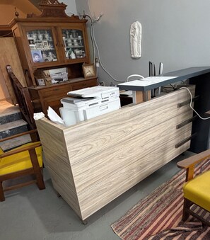 Una habitación con un escritorio de madera, una estantería, una silla y una alfombra estampada.