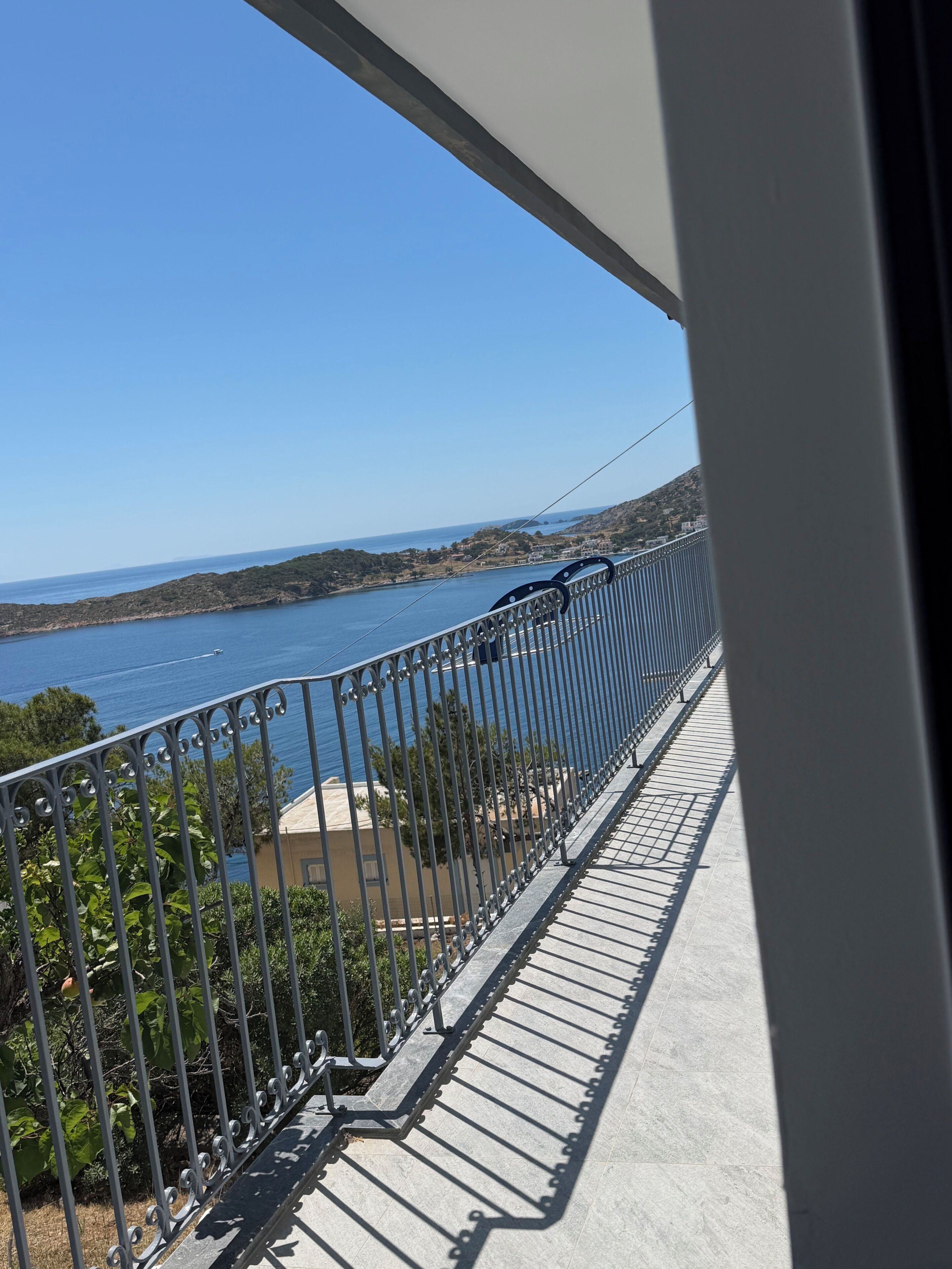 A balcony with a view of a body of water and distant hills.