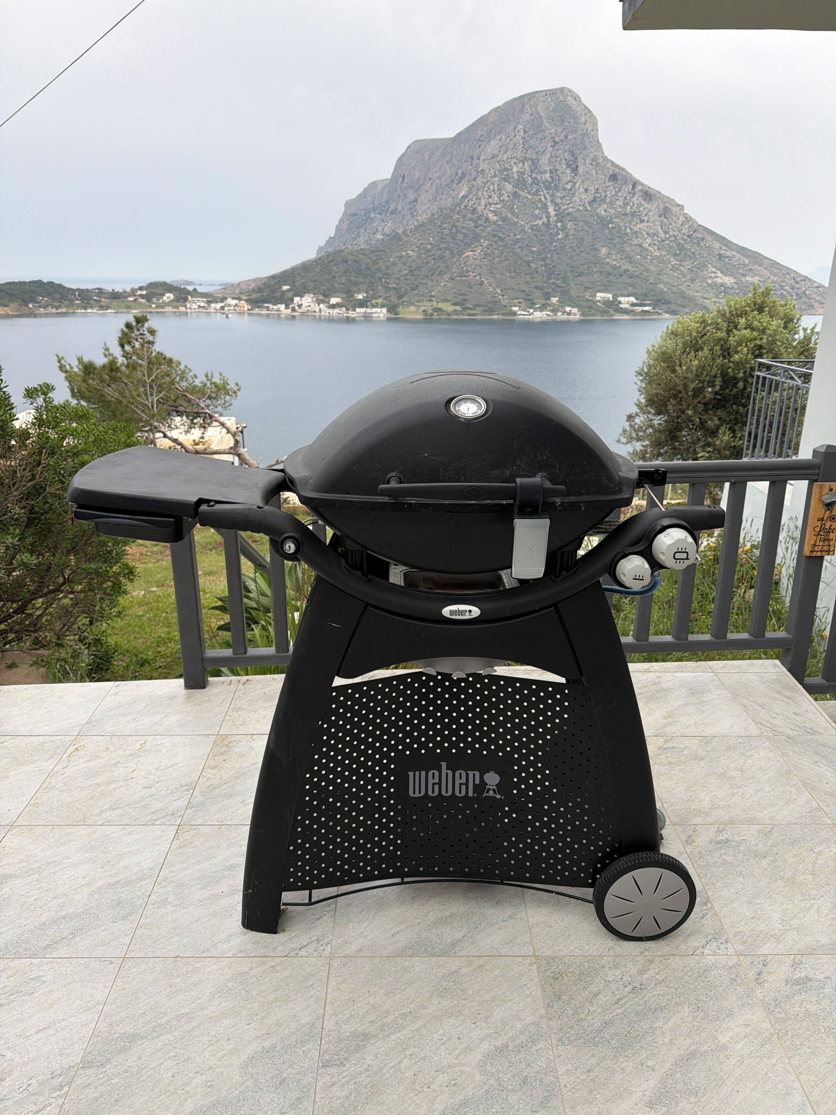 Een Weber barbecue met uitzicht op een meer en een berg op de achtergrond.