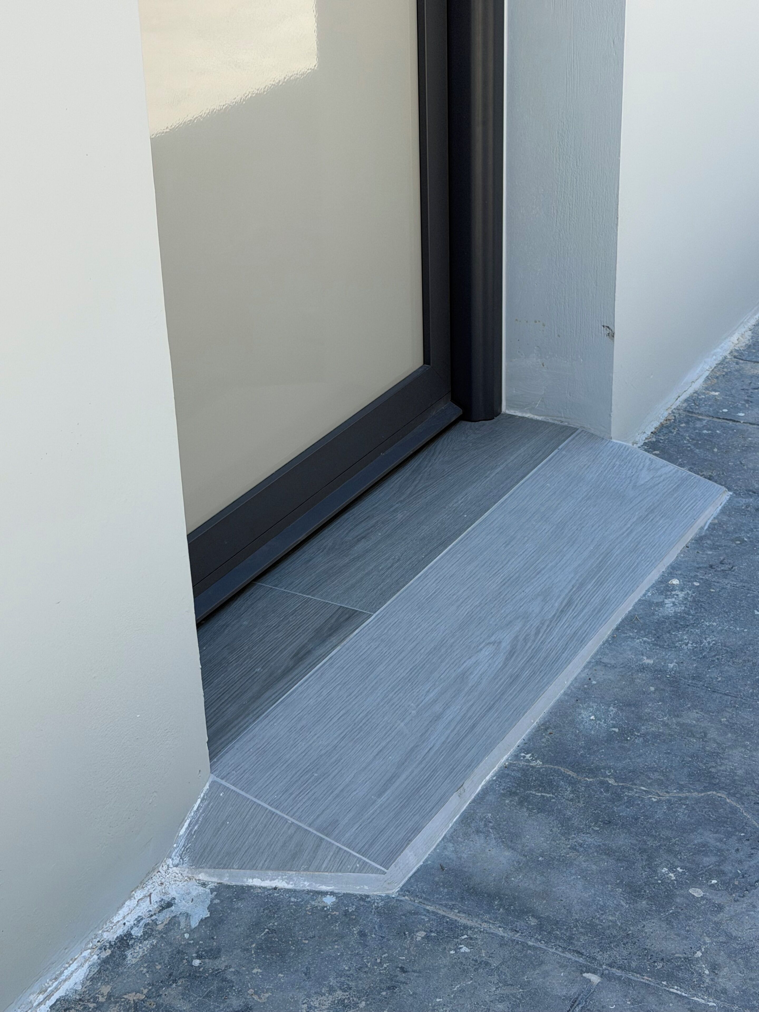 A corner of a room with a grey tiled floor and a beige wall.