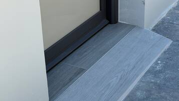 A corner of a room with a grey tiled floor and a beige wall.