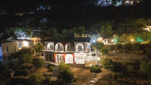 A two-story building with a central courtyard, multiple arches, and a small shop on the ground floor. - Kaloniki Rooms & Suites (Mirties)