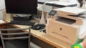 Un espacio de trabajo con computadora, monitor, teclado, ratón, impresora y ventilador.