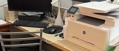 A workspace with a computer, monitor, keyboard, mouse, printer, and fan.