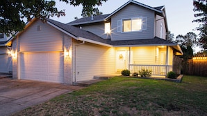 A two-story house with a garage, a front porch, and a well-maintained lawn. - Charming Retreat: King Bed, Full Kitchen & Spacious Backyard. Perfect Location! (Hillsboro)