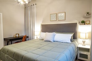 Een keurig opgemaakte slaapkamer met een bed, nachtkastjes, een bureau en een stoel.
