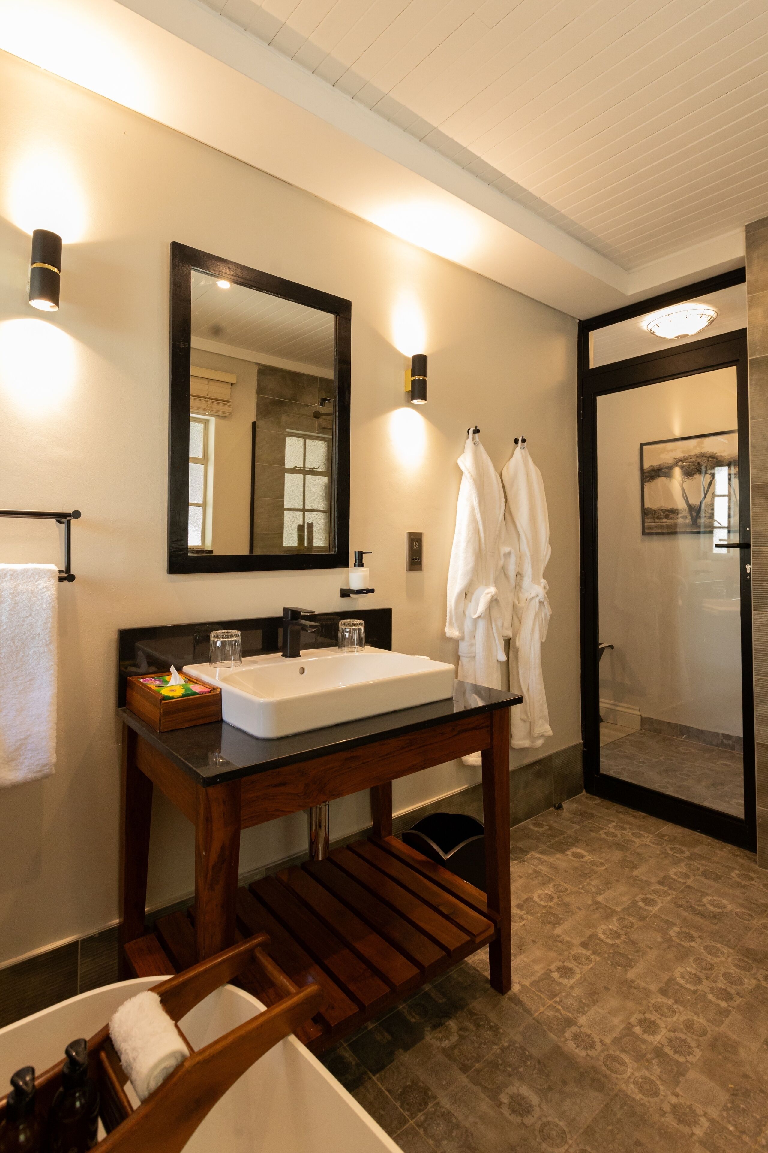 A modern bathroom with a wooden vanity, a large mirror, and a glass shower enclosure.