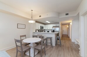 Une cuisine moderne avec des meubles blancs, un îlot central et un coin repas comprenant une table ronde et des chaises.