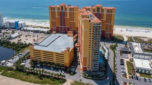 A high-rise hotel with multiple floors, a parking lot, and a beach view. - Calypso Tower 3  507, 3 Bed,  2 Bath w Gulf Views! (Panama City Beach)