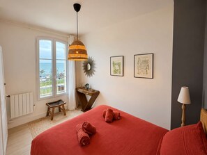 A bedroom with a bed, a window with a view, a bedside table, and a lamp.