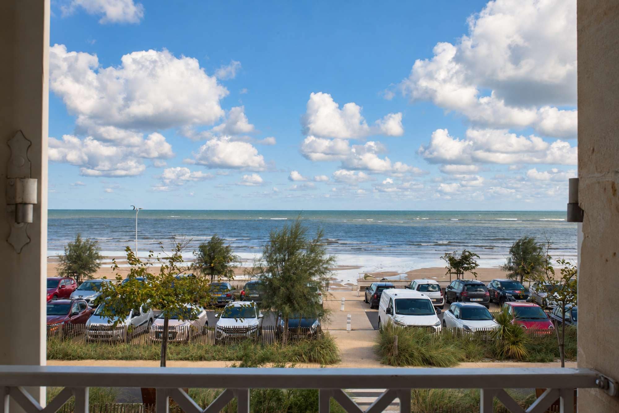 A view of a beachside parking area with cars and a clear sky.