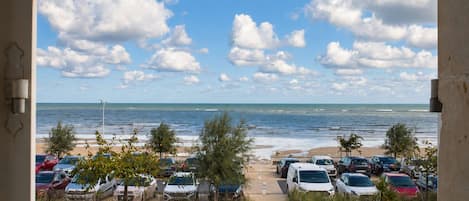 A view of a beachside parking area with cars and a clear sky.