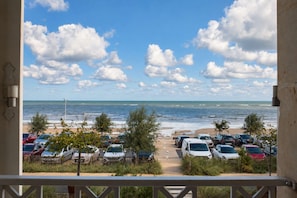 A view of a beachside parking area with cars and a clear sky. - Bel Horizon, a charming apartment with a balcony and ocean view   (Luc-sur-Mer)