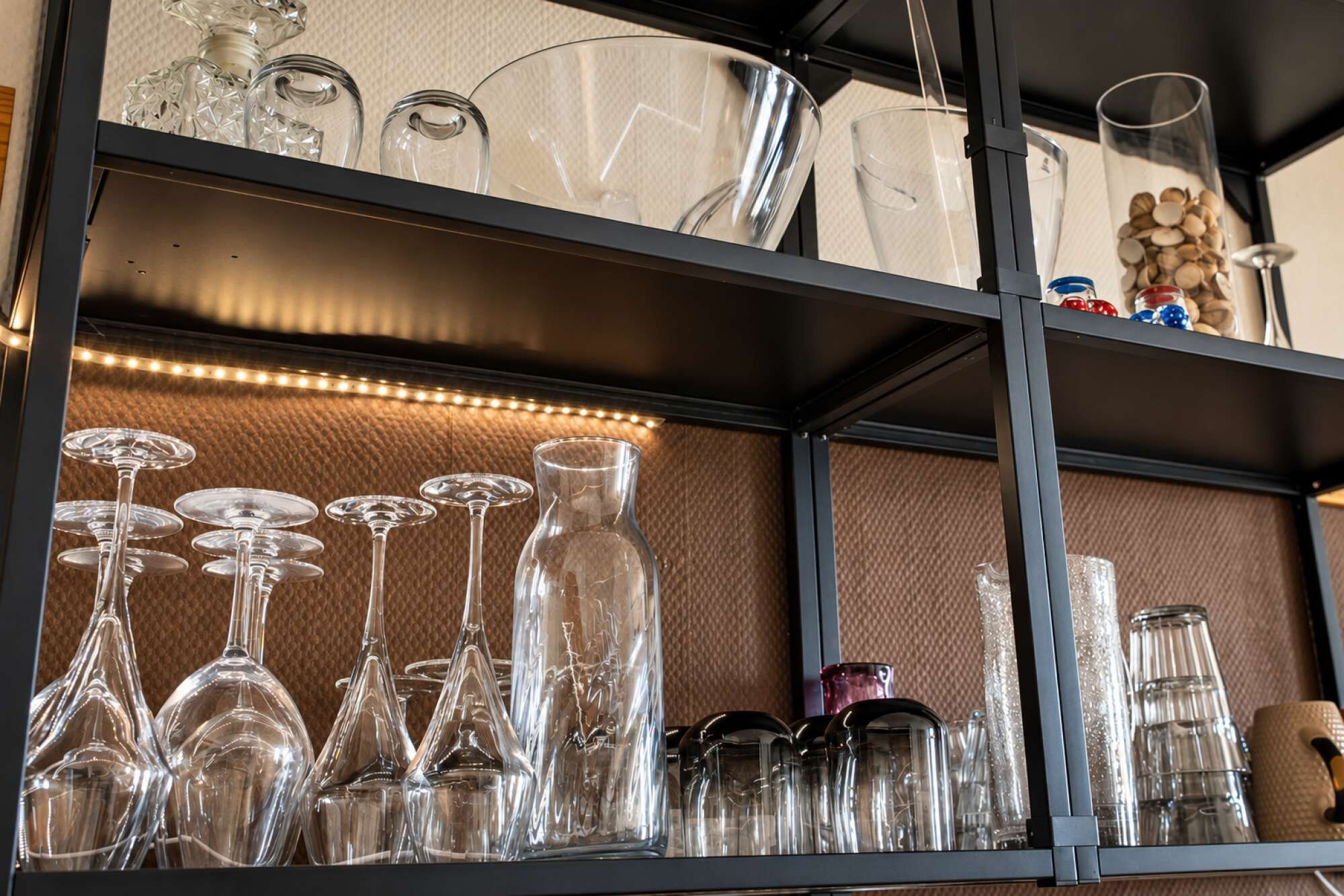 A shelf with various glassware, including wine glasses and tumblers.