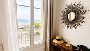 A room with a large window, a sunburst mirror, a wooden desk, and a woven rug.