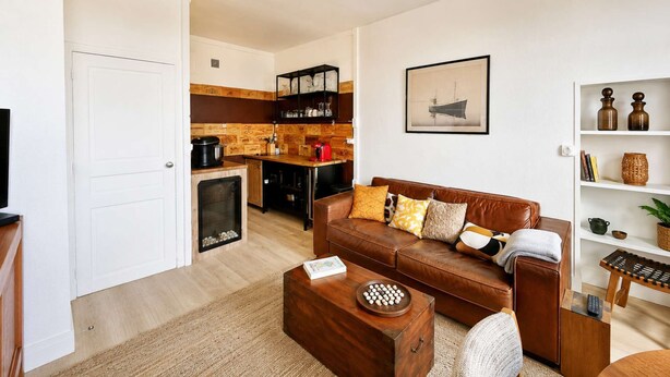 A compact living space with a kitchenette, a sofa, a coffee table, and a bookshelf.