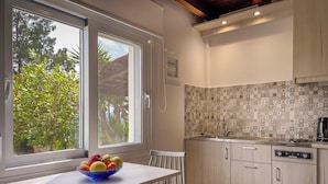 Una cocina moderna con un ventanal grande, un cuenco de fruta sobre la mesa y un salpicadero de azulejos.