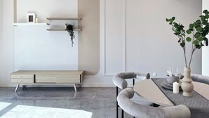 Un comedor moderno con una mesa redonda, sillas tapizadas en gris, un banco e iluminación colgante.