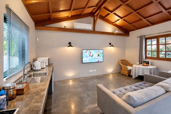 Una cocina moderna con horno empotrado, cafetera y televisor montado en la pared.