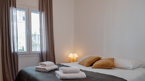 Une chambre d’hôtel avec un lit, deux oreillers, une lampe et une fenêtre avec des rideaux.