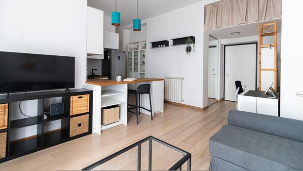 Un espace de vie moderne comprenant un téléviseur à écran plat, une table à manger en bois et un canapé gris.
