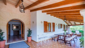 A spacious patio with a wooden table and chairs, a tiled floor, and a view of greenery outside. - Villa La Rosaleda - By Dream Villas Pollensa (Pollensa)
