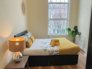 Relax in a serene space with a large bed, nightstand, and potted plant.