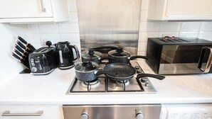 A kitchen with a stove, pots, a toaster, and a microwave. - 2BDR flat in Hammersmith with Wi-Fi & Workspace near Shepherd's Bush & Westfield (London)