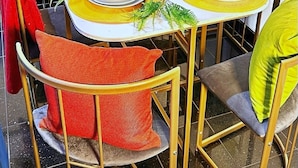 Une table à manger dressée avec des assiettes, des verres et des bouteilles, entourée de chaises dotées de coussins.