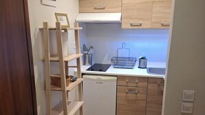 A compact kitchen with wooden cabinets, a white dishwasher, a small sink, and a wooden ladder.