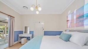 Une chambre à coucher avec un grand lit, une commode, un miroir et un luminaire au plafond.