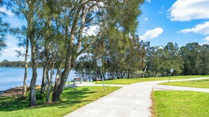 Un parc avec un chemin en béton, des bancs et un lac.
