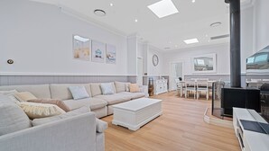 Un salon spacieux avec un grand canapé, un coin repas et une cuisine équipée d’une cuisinière.