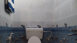 Kylpyhuone, jossa on wc, suihku ja vihreä ämpäri.