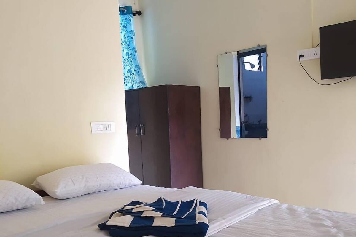 A hotel room with a bed, a wardrobe, a mirror, and a TV.