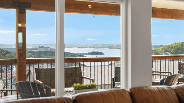 En balkon med udsigt over en sø og fjerne bygninger.