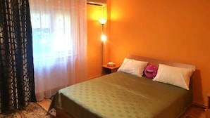 A hotel room with a bed, a nightstand, a lamp, and a window with curtains. - Central Apartment Bucharest - Vitan Mall (Bucuresti)