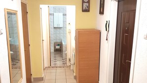 A hallway with a tiled floor, a wooden door on the right, and a mirror on the left. - Central Apartment Bucharest - Vitan Mall (Bucuresti)