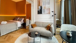Une chambre d’hôtel moderne équipée d’un lit, d’un canapé, d’une table basse et d’un fauteuil.