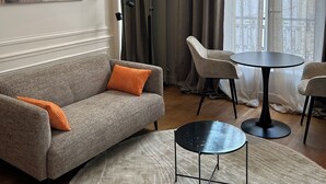 Un salon moderne avec un canapé gris, une table ronde noire et un grand tableau abstrait accroché au mur.