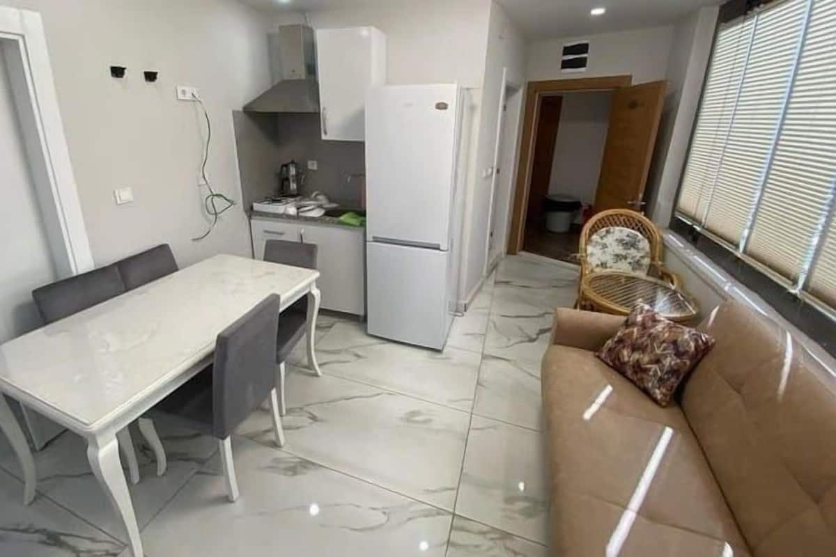 Una cocina compacta con una mesa de comedor, un refrigerador y un sofá.