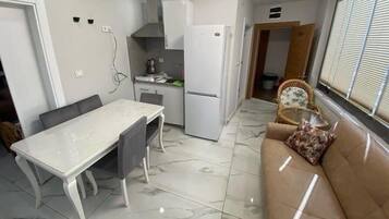 A compact kitchen with a dining table, a refrigerator, and a sofa.