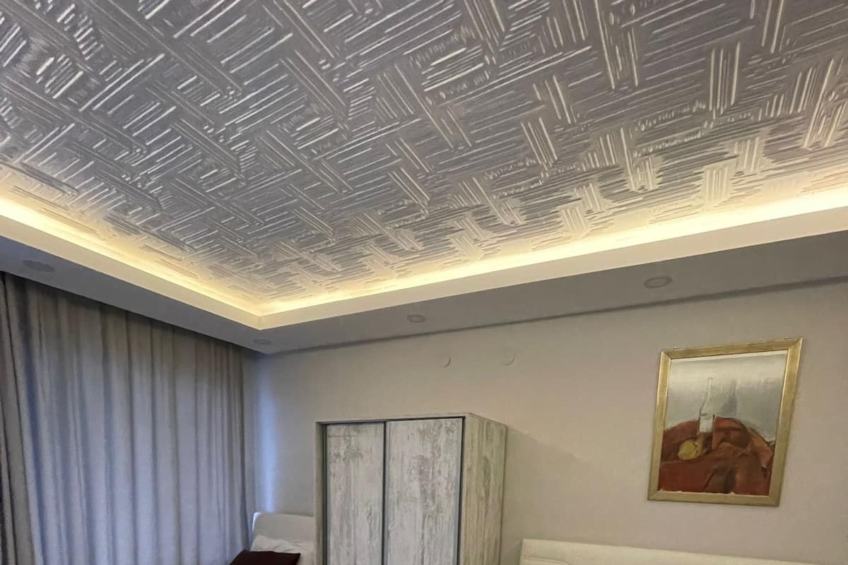 Habitación de hotel con dos camas, un armario y un techo con diseño geométrico.