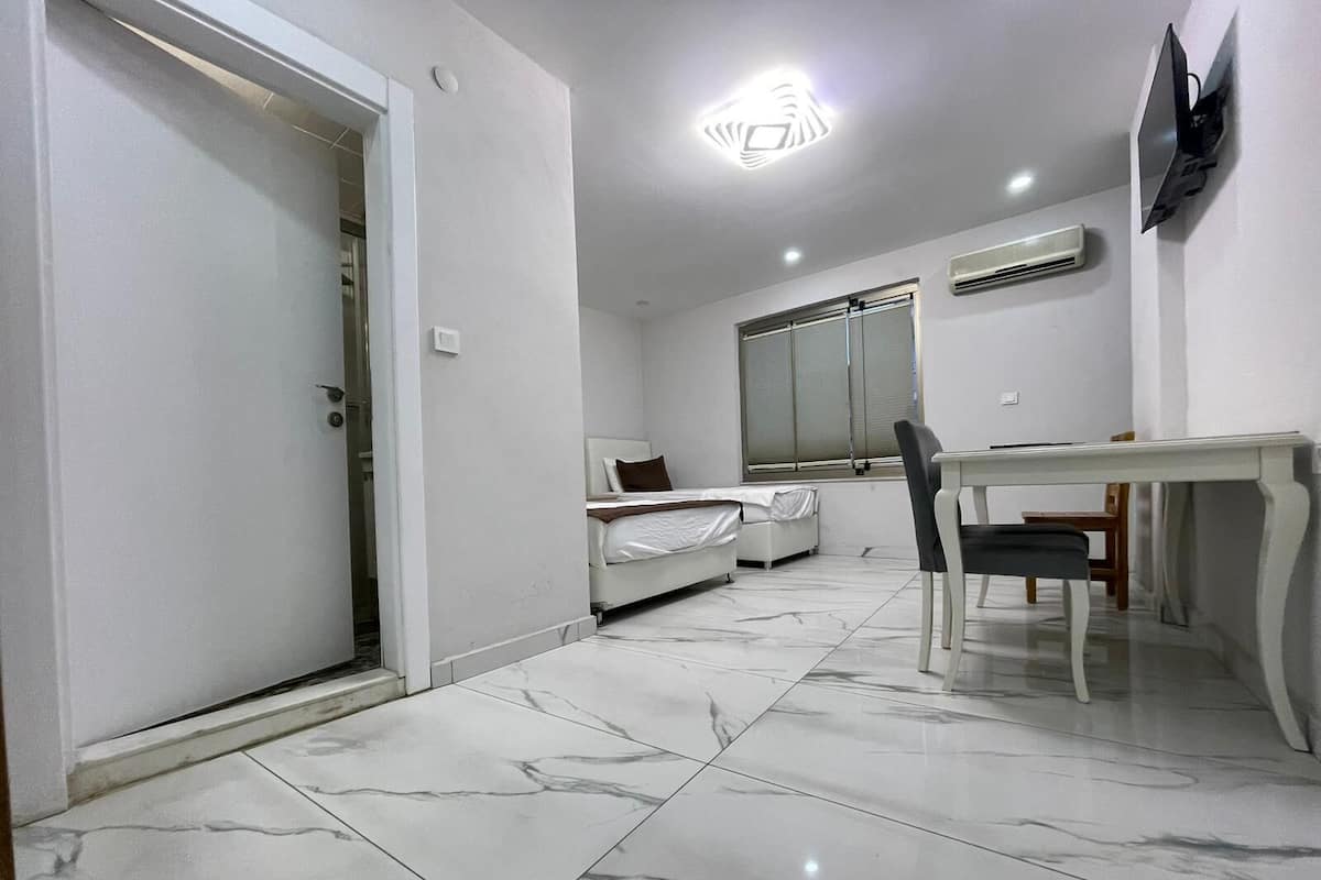 Habitación de hotel con cama, escritorio, silla, televisión y aire acondicionado.
