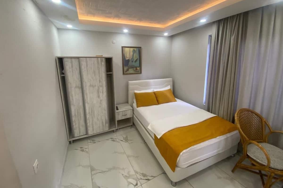 Una habitación de hotel moderna con cama, armario, silla y un cuadro en la pared.