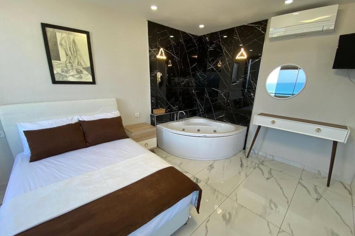 Una habitación de hotel moderna con una cama grande, un baño independiente con bañera y un tocador con espejo.