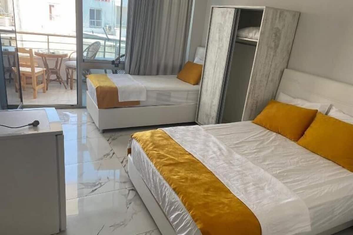 Habitación de hotel con dos camas, un escritorio y vistas a la calle.